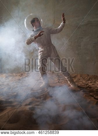 Fear Of The Unknown On Alien Planets. An Astronaut In A White Spacesuit Walks Through An Abandoned C