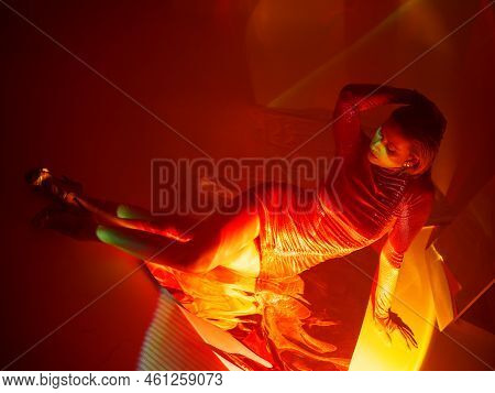 Glamorous Portrait Of A Young Beautiful Blonde In A Stylish Scarlet Short Dress, Sitting On The Floo