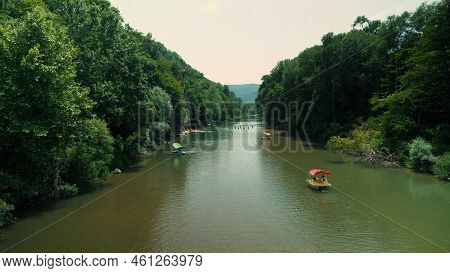 Colorful Pedal Catamarans Float On A Beautiful River With Green-colored Water. A Dense Forest Grows 
