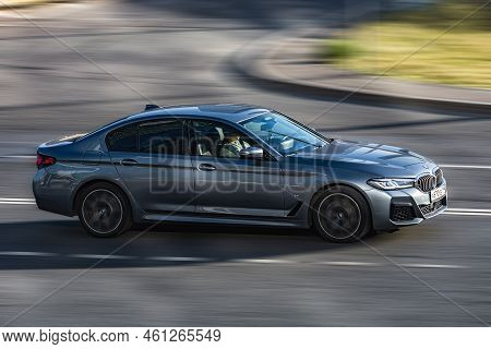 Car Bmw 5 Series On The Road In Motion. Fast Speed Drive On City Road. Side View Of Moving Gray Car 
