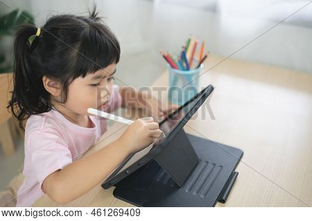 Asian Girl Looking And Touch On White Screen At The Tablet Screen Attentively. Overstimulated Childr