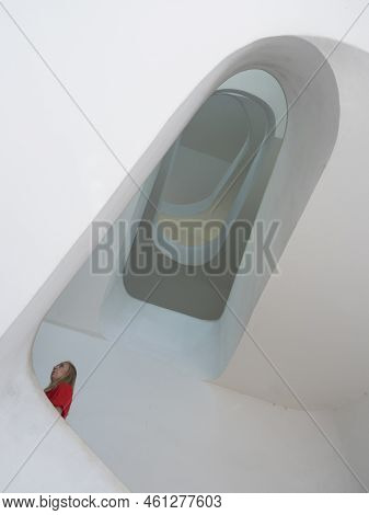 Lisbon, Portugal, October 24, 2021: Woman In Red Walking At White Spiral Staircase Of Elevador De Sa