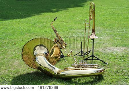 Various Musical Brass Instruments Like Sousaphone, Trombone And Saxophone Placed On The Lawn In The 