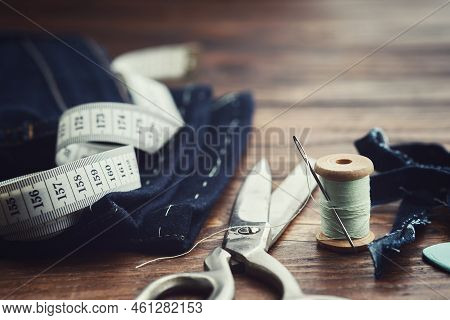 Shortening Jeans. Measuring Tape, Scissors, Spools Of Thread And Chalk On Wooden Table. Jeans Cuttin