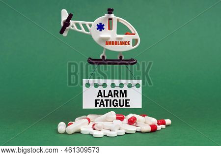 Medical Concept. On A Green Surface, An Ambulance Helicopter, Pills And A White Sign With The Inscri