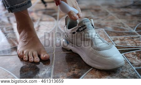 Hallux Valgus On Legs Of A Woman With Silicone Retainer Puts On Sneakers Closeup. Foot Joint Deformi