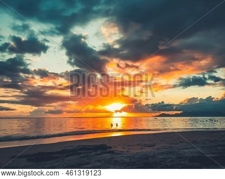 Multi Color Bright Sunset Over Sea Sand Beach. People Relax And Watch Sun Down Landscape. Blue And O