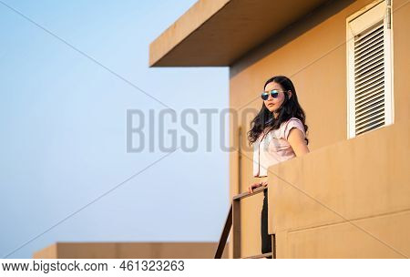 Beautiful Asian Woman Is Standing On The Stair And Looking Over To The Sky In The Sunset Time At Roo
