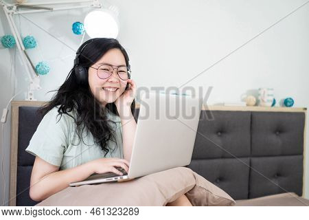 Glasses Beautiful Asian Woman Is Working On Her Laptop In The Bedroom With A Pastel Green - Brown Co