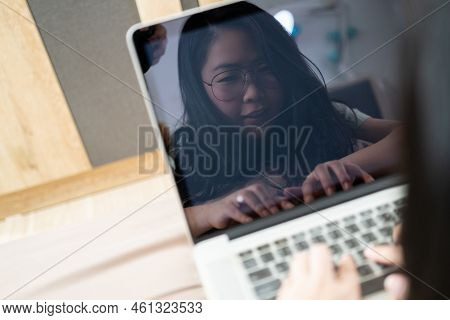 The Reflection Of Beautiful Asian Woman From Laptop Screen. She Plays Laptop And Lays On The Bed In 