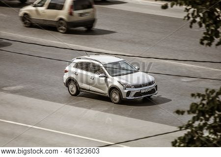 Silver Kia Rio Car Driving On A City Road. Aerial Side View Of Compact Hatchback Kia Kx Cross Speedi