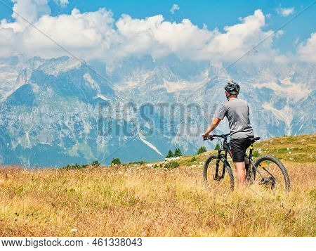 Teenager Sit On Modern Mtb And Watching From Hill Peak To Opposite Stonny And Snowy Peaks. Dolomite 