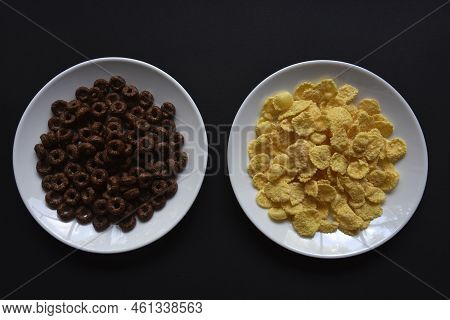 Breakfast Of Chocolate And Honey Cornflakes On White Plates On A Black Background. Delicious Breakfa