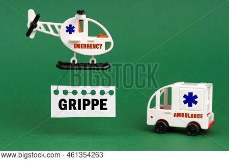 Medical Concept. On A Green Surface, An Ambulance Car And A Helicopter With A Sign - Grippe