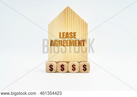 Real Estate And Business. On A White Surface Stands A Wooden Model Of A House With The Inscription -