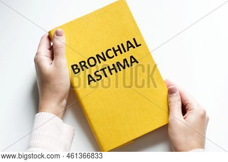 Bronchial Asthma Text On A Yellow Notebook In The Hands Of A Person Against The Background Of A Brig