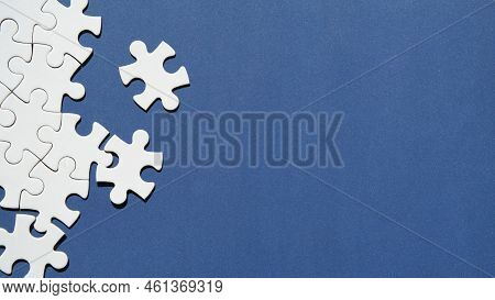 Jigsaw Puzzle Pieces Half Assembled And Separate. Top View, Flat Lay On Monochromatic Abstract Blue 