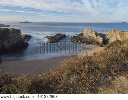 View Of Empty Praia Dos Buizinhos Sand Beach With Long Exposure Blurred Ocean Waves And Sharp Rock A