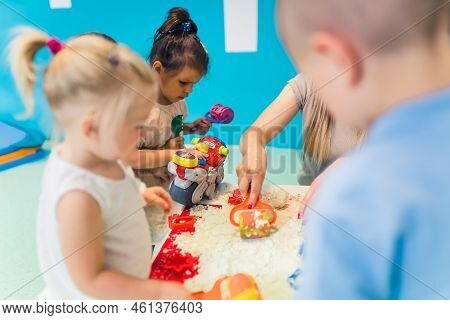 Relaxing Sensory Play With Moldable Kinetic Sand At Nursery School. Toddlers With Their Teacher Havi
