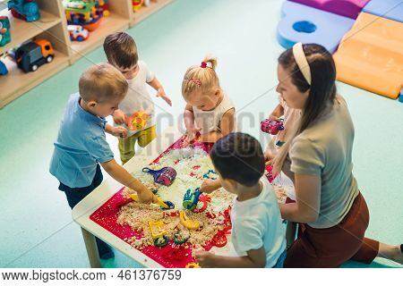 Calming Sensory Play With Moldable Kinetic Sand At Nursery School. Toddlers With Their Teacher Havin