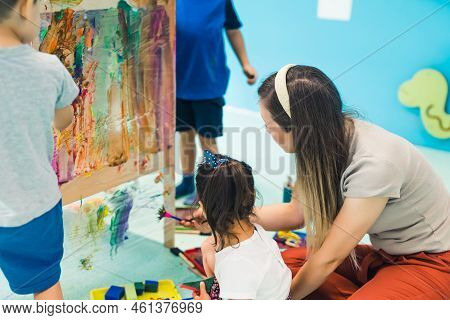 Cling Film Painting. Toddlers Painting With A Sponge, Brushes And Paints On A Cling Film Wrapped All