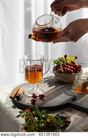Female Hand Pours Hot Herbal Tea Into A Glass Mug. Vertical