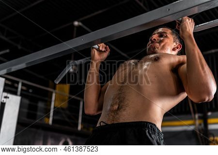 Muscular And Athletic Latin Man Working His Chest Doing Pull-ups. A Hispanic Man Working Out His Bod