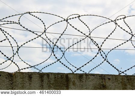 Barbed Wire On The Fence. Fencing Stainless Steel Barb Wire With Sharp Edges On A Massive Concrete W