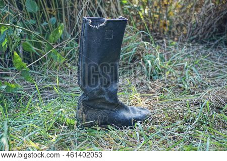One Old Black Dirty Tarpaulin Boot Stands In The Green Grass In Nature