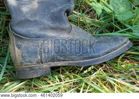 One Old Black Dirty Tarpaulin Boot Lies In The Green Grass In Nature