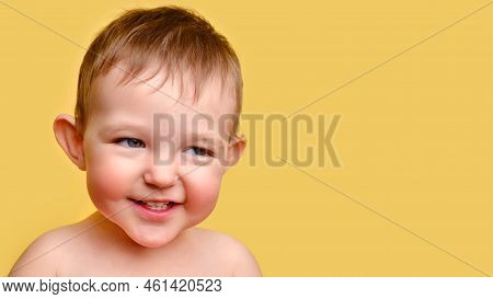 Sly Toddler Baby, Studio Yellow Background, Copy Space. Portrait Of An Insidious Child With Red Chee
