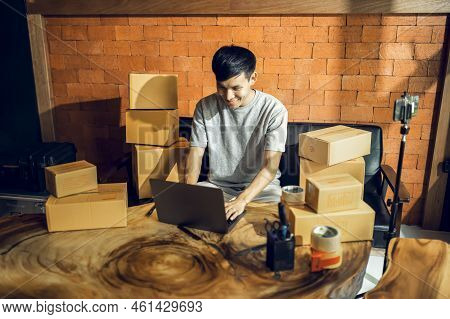 An Asian Man Uses A Mobile Phone To Take Orders And Display Items In A Box That Records Live Streami
