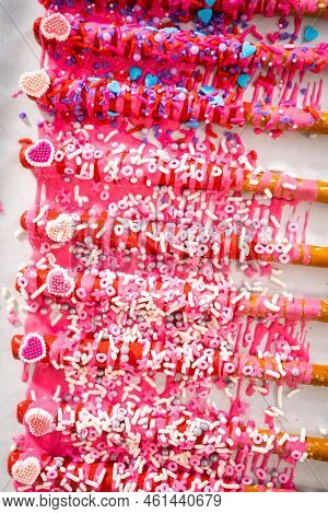 Drizzling Melted Chocolate Over Chocolate-dipped Pretzels Rods And Decorating With Sprinkles To Make