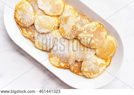 Flat Lay. Freshly Made Small Pancakes On A Kefir Base Garnished With Powdered Sugar.
