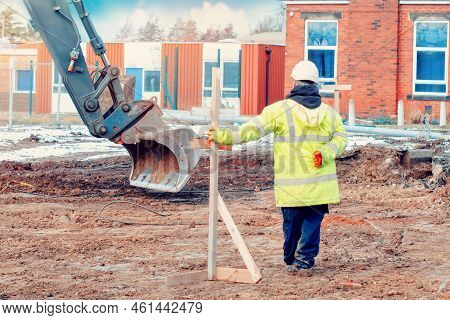 Excavator And Workers At Construction Site In Winter