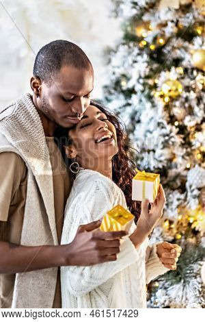 A Happy Couple Of Mulattoes Exchange Gifts With Each Other. Celebrating Joint Family Events.