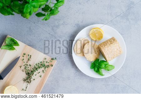Top View Raw Tempeh Or Tempeh, Made Of Fermented Soybean Seeds. Tempeh Slices On Plate With Herbs. S