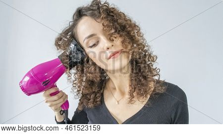 Young Woman Makes Curls With A Blow-dryer With A Diffuser. Hair Care Concept. A Girl Is Styling Her 