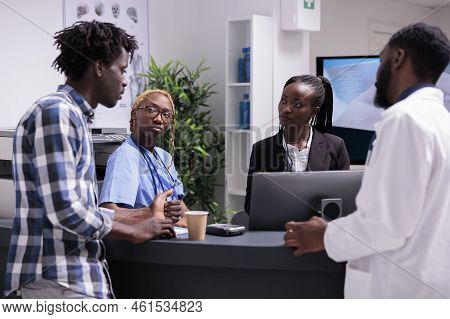 All African American Team Talking To Patient At Hospital Reception Desk To Give Healthcare Support. 