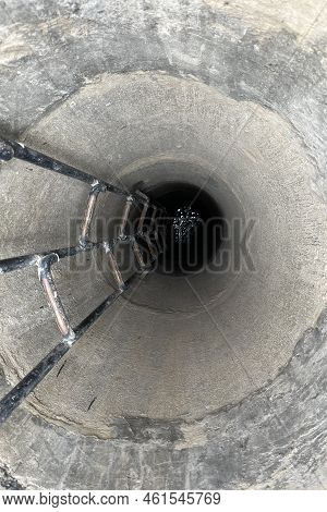 Deep Concrete Well, Water At The Bottom Of The Well, Stairs Down The Well. High Quality Photo