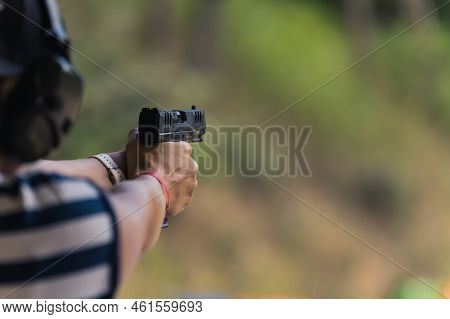 Man Practicing Aiming With A Gun At The Shooting Range, Medium Closeup Blurred Background. High Qual