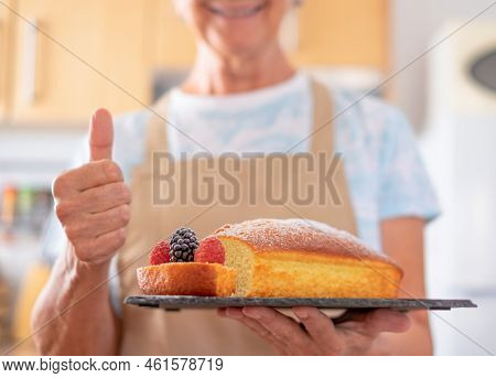 Senior Woman In The Kitchen Holding Her Home Made Plumcake. Cooking At Home. Delicious And Beautiful