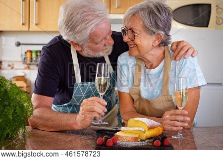 Beautiful Senior Couple In The Home Kitchen Holding A Glass Of Wine Ready To Eat Their Homemade Plum