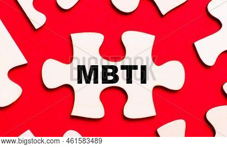 On A Bright Red Background, White Puzzles. In One Of The Pieces Of The Puzzle, The Text Mbti