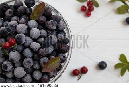Frozen Blueberries In A Glass Bowl, Highlighted On A White Background With A Space To Copy.
