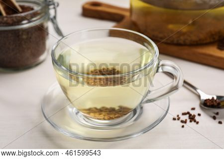 Buckwheat Tea In Glass Cup And Granules On White Wooden Table, Closeup