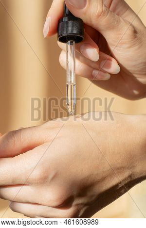 Close-up Of Pipette With Collagen Moisturizing Hyaluronic Serum In Womans Hand In Rays Of Sunlight. 
