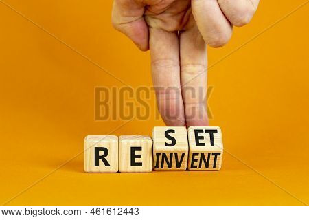 Reinvent And Reset Symbol. Businessman Turns Wooden Cubes And Changes The Concept Word Reinvent To R