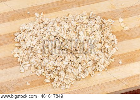 Heap Of The Raw Thick-rolled Oats On The Bamboo Cutting Board, Close-up