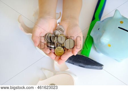 Childrens Palms Hold Coins, Top View, Close-up. Broken Piggy Bank, Hammer And Piggy Bank On The Tabl